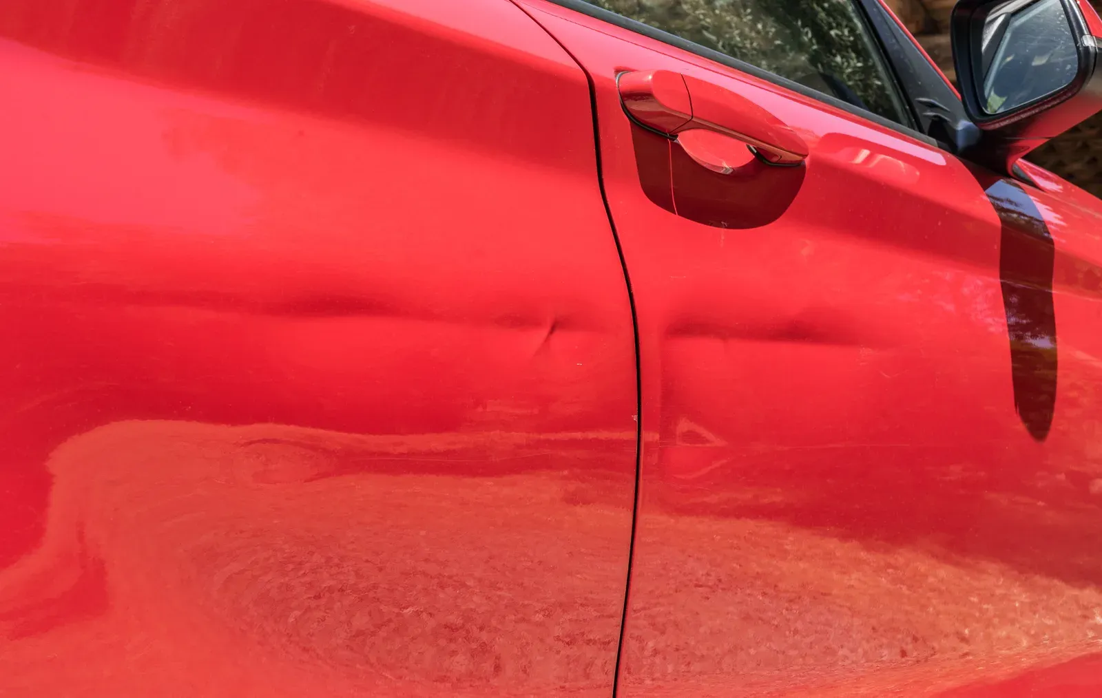 Damaged door panel on a parked car brought in for repair in North York
