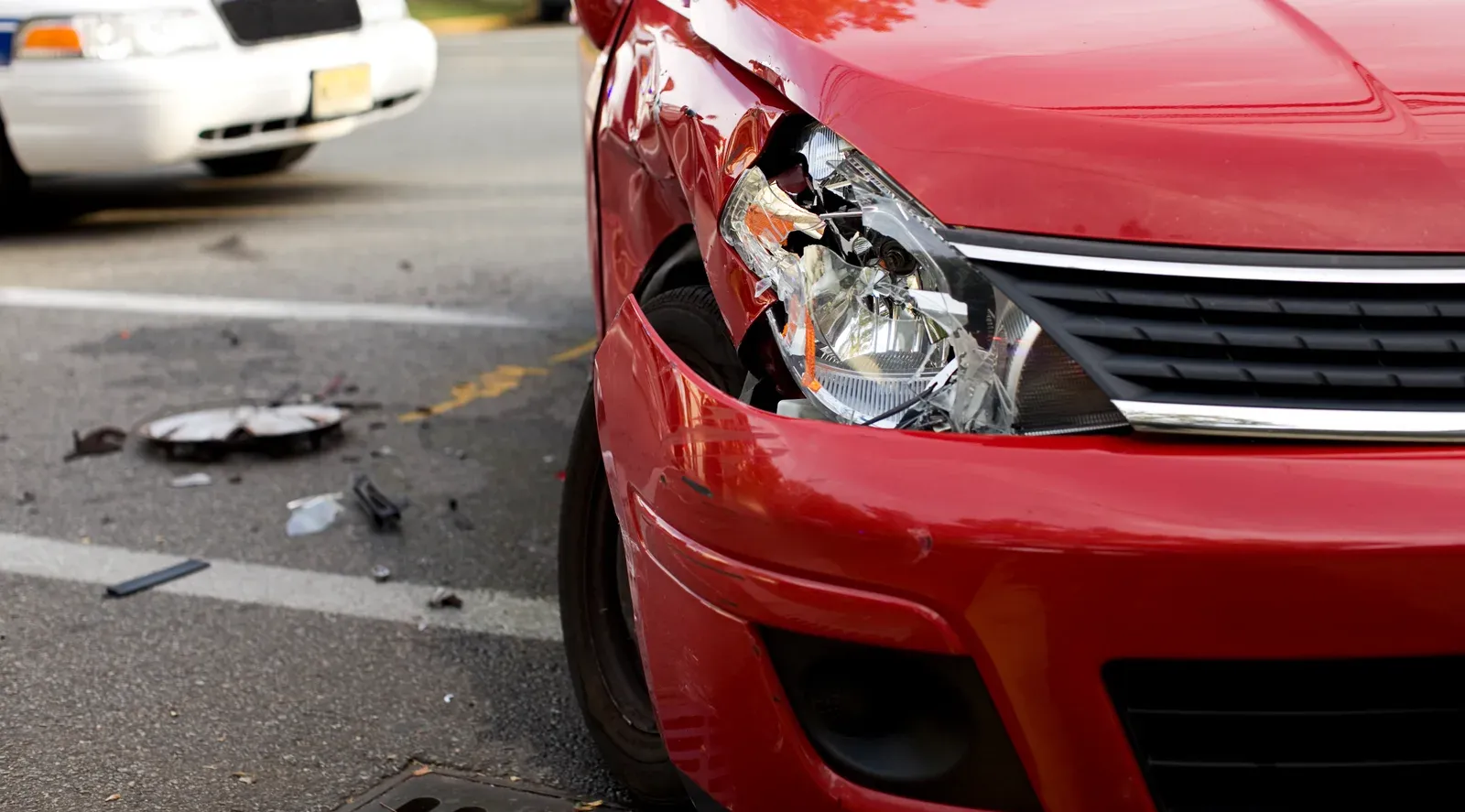 Cracked headlight and front-end damage on a car before repair