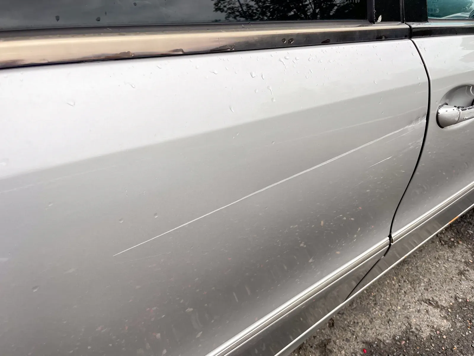 Deep scratch through the paint on a vehicle panel before refinishing
